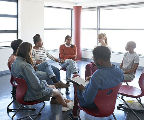 A group of people having a meeting style conversation inside a building